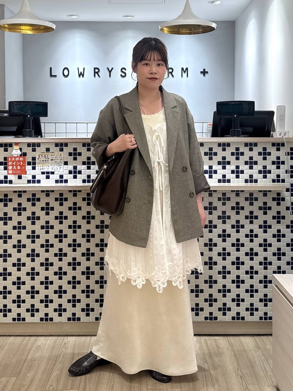 ホワイト系のスカート、ブラウン系のテーラードジャケット、ブラウン系のローファーを着用したレディースの春コーディネートの2枚目の写真