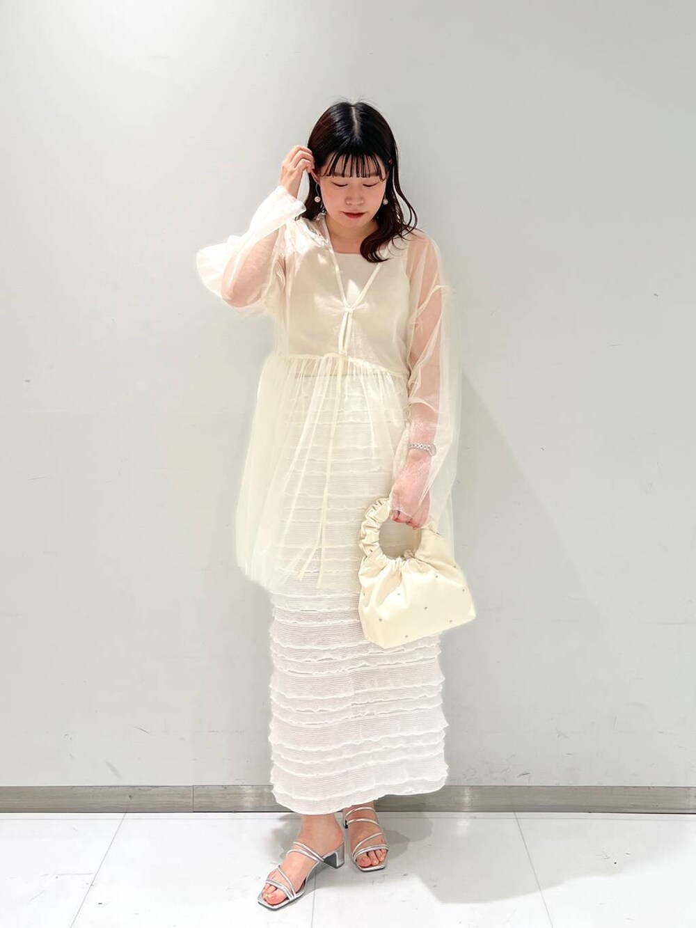 ホワイト系のタンクトップ、ホワイト系のスカート、ベージュ系のハンドバッグを着用したレディースの春コーディネートの2枚目の写真