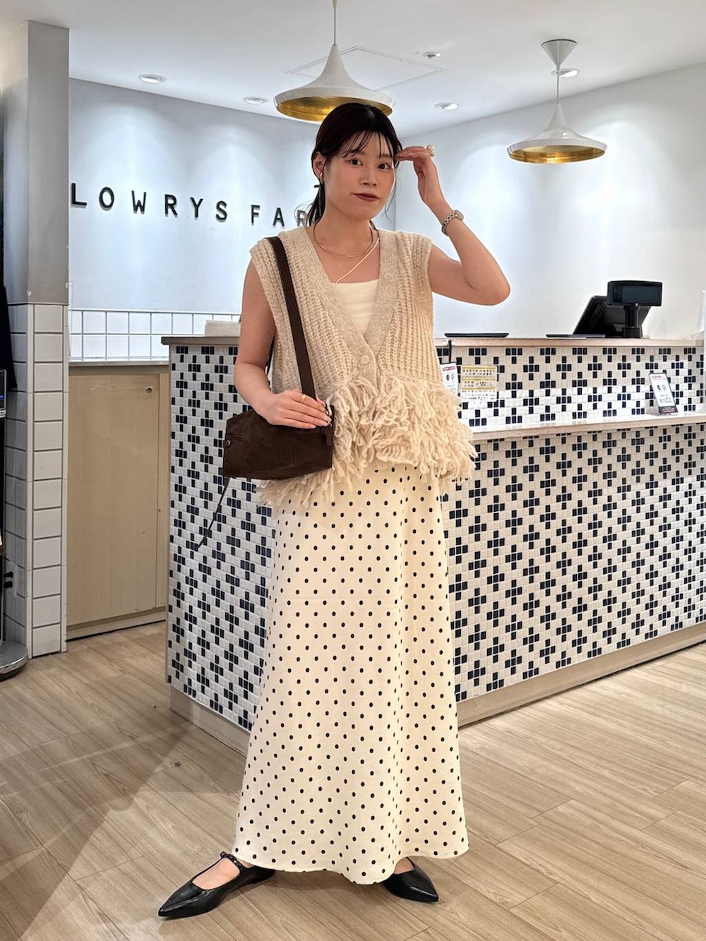 ホワイト系のスカート、ブラウン系のショルダーバッグ、ブラック系のパンプスを着用したレディースの秋コーディネートの2枚目の写真