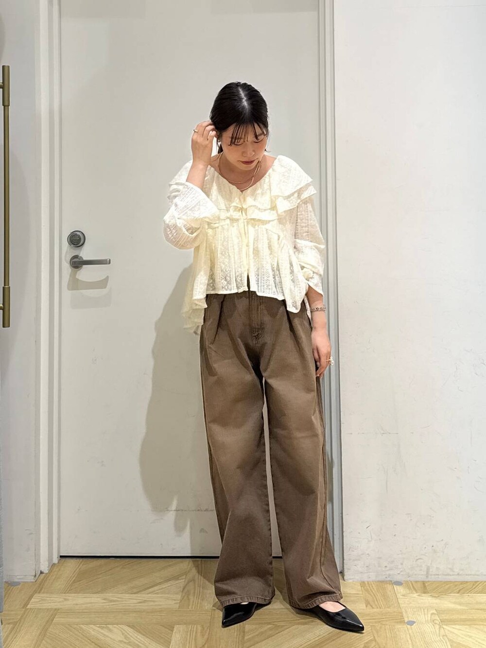 ブラウン系のデニムパンツ、ブラック系のパンプス、ホワイト系のシャツ/ブラウスを着用したレディースの夏コーディネートの3枚目の写真