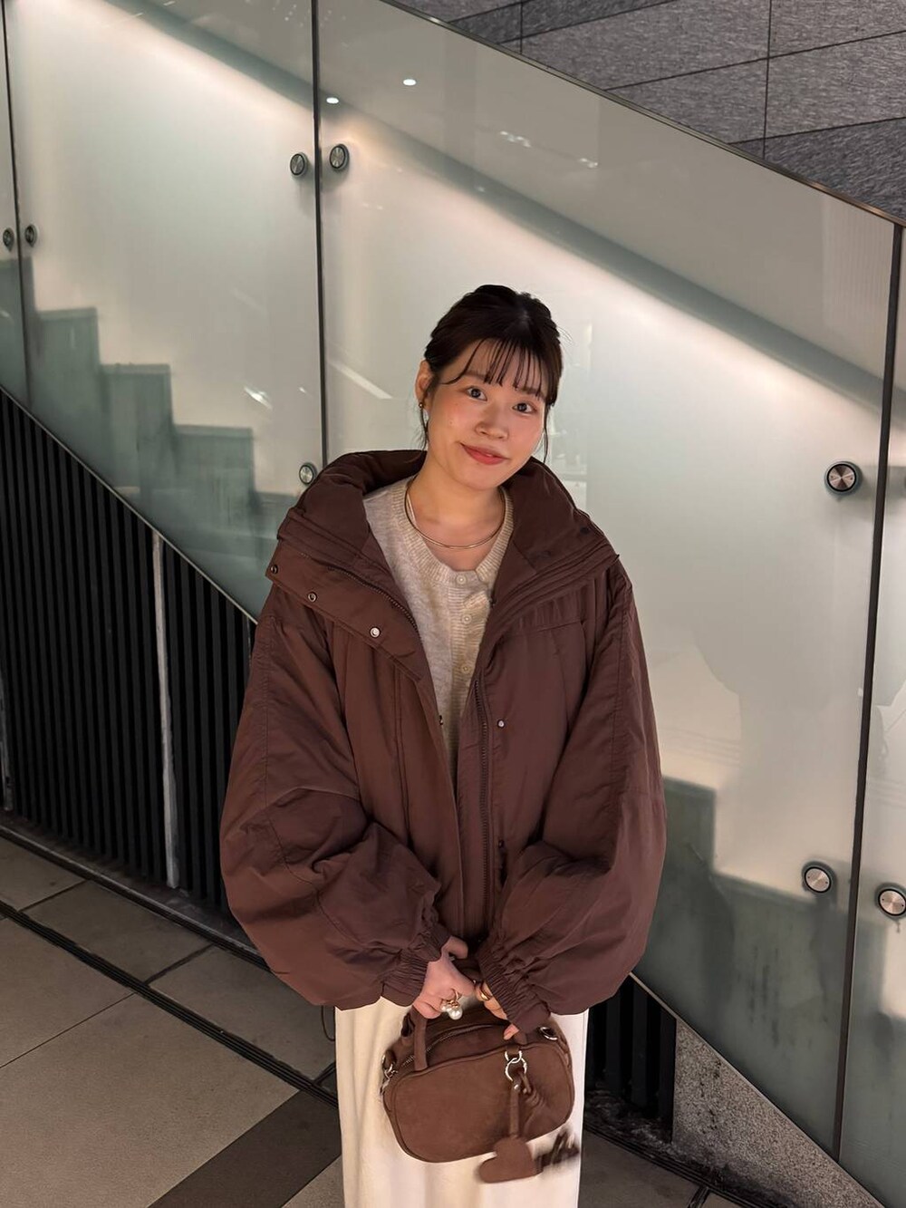 ブラウン系のその他アウター、ホワイト系のスカート、ブラウン系のボストンバッグを着用したレディースの秋コーディネートの2枚目の写真