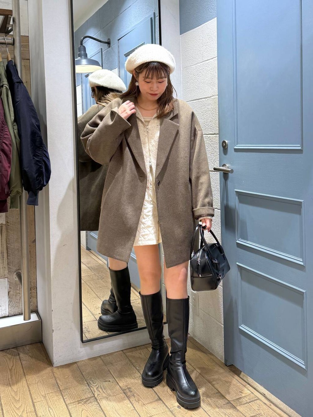 ブラウン系のチェスターコート、ホワイト系のその他パンツ、ブラック系のブーツを着用したレディースの秋コーディネートの3枚目の写真