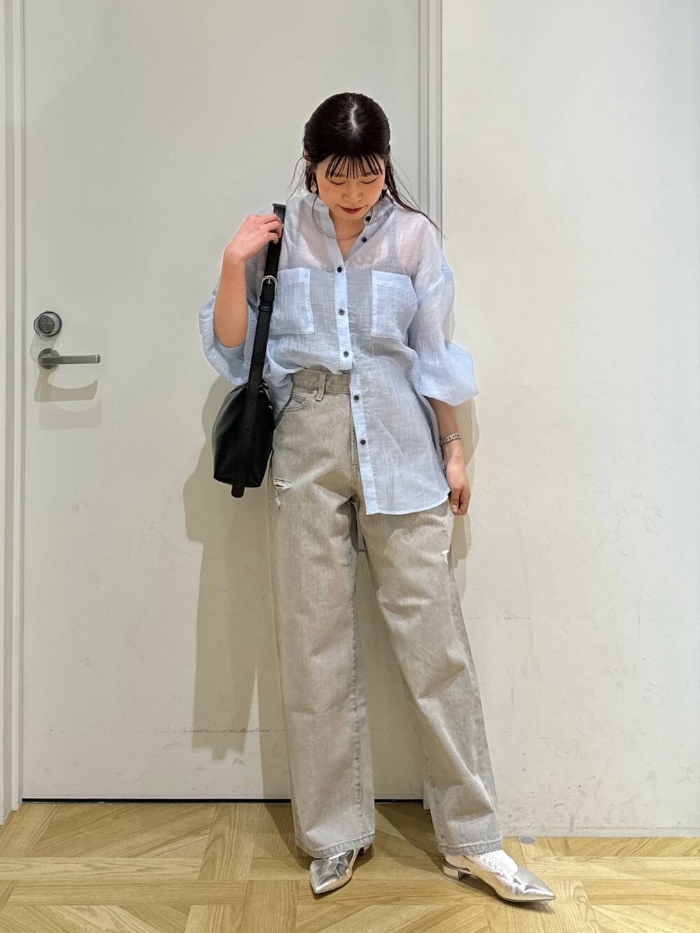 グレー系のデニムパンツ、シルバー系のパンプス、ブラック系のショルダーバッグを着用したレディースの春コーディネートの2枚目の写真