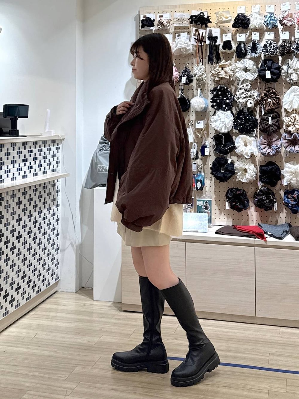 ブラウン系のその他アウター、ホワイト系のスカート、ブラック系のブーツを着用したレディースの秋コーディネートの2枚目の写真