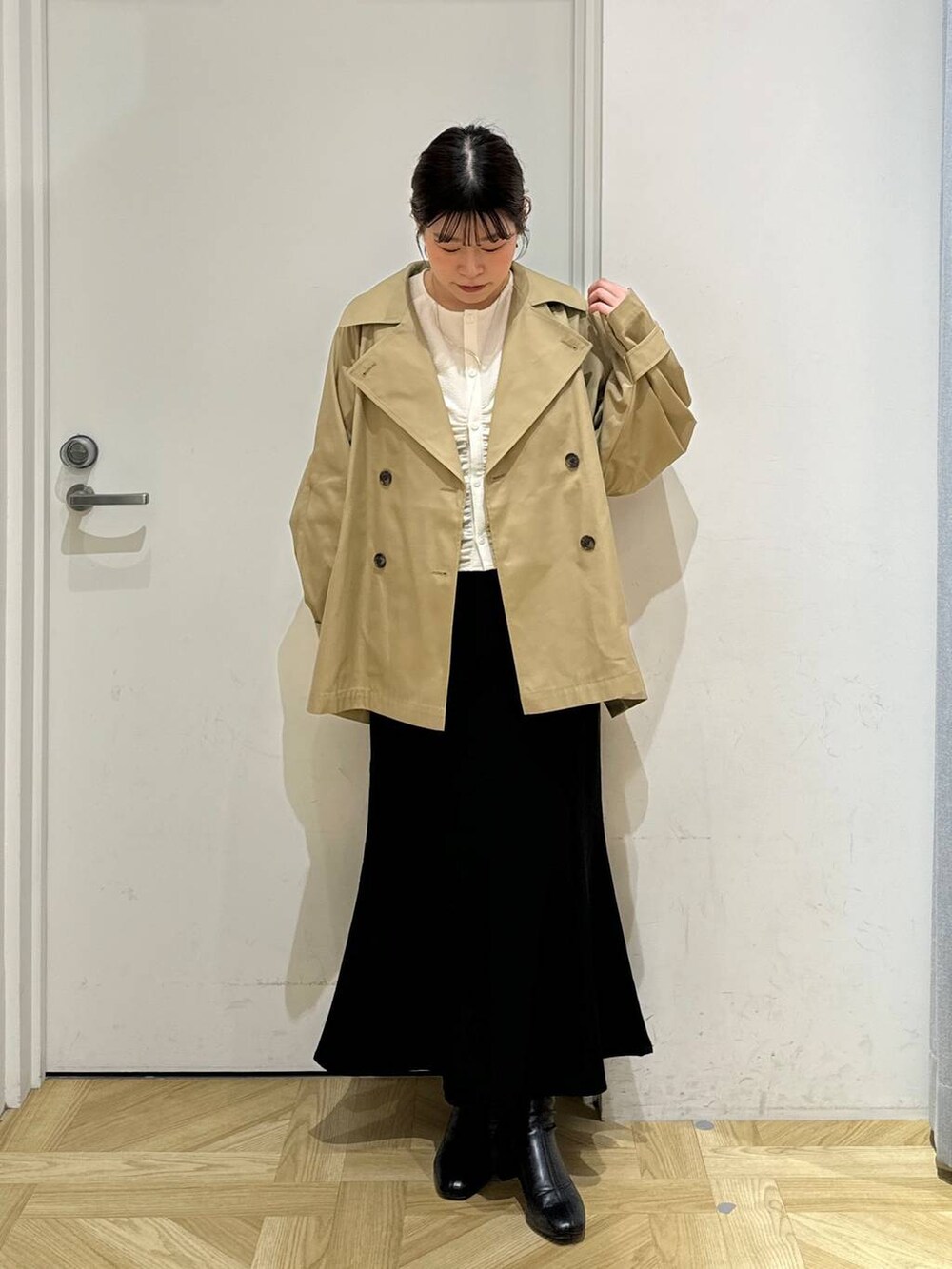 ブラック系のブーツ、ホワイト系のシャツ/ブラウス、ブラウン系のトレンチコートを着用したレディースの春コーディネートの2枚目の写真