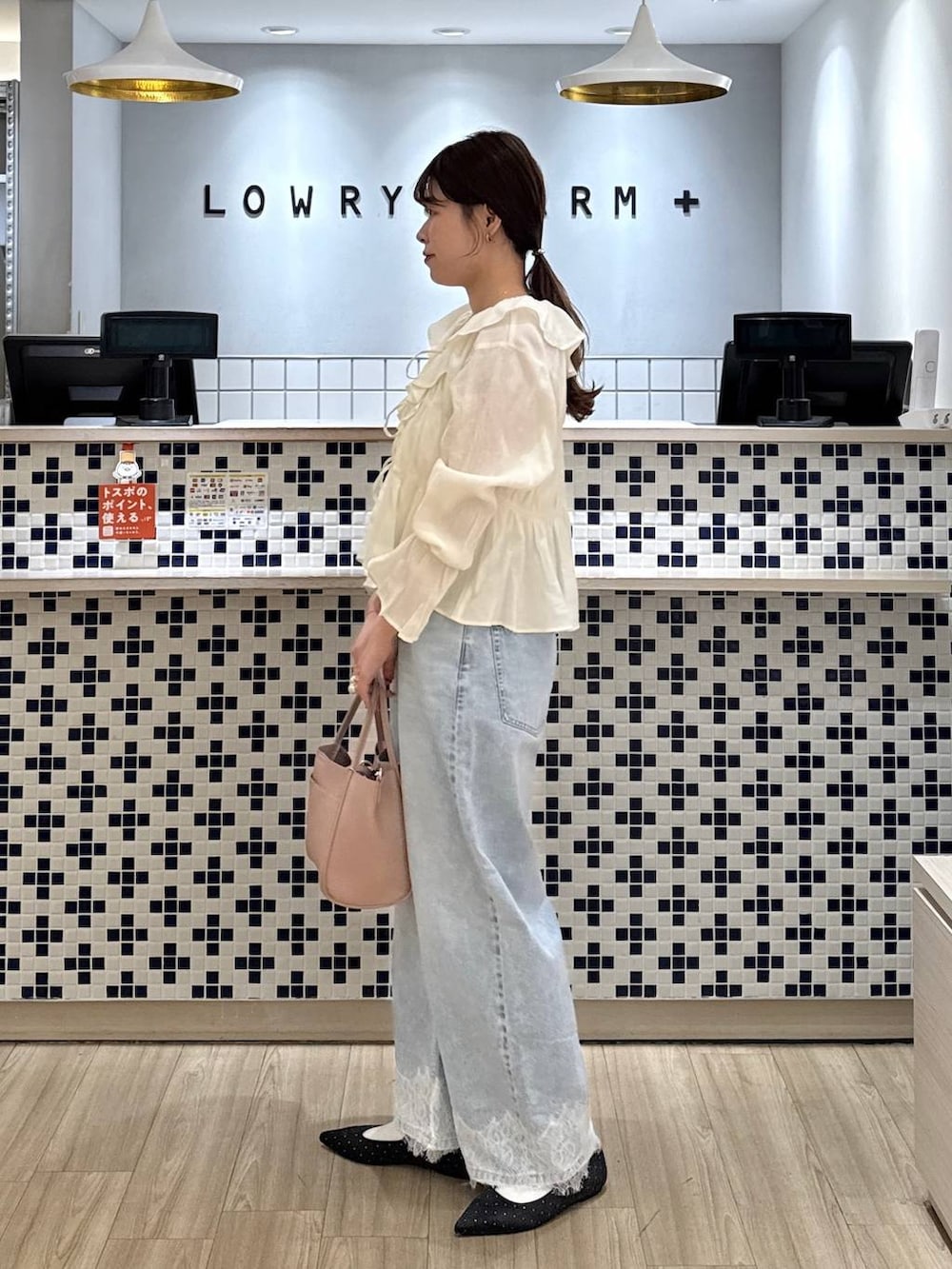 ホワイト系のショルダーバッグ、ブラック系のパンプス、ブルー系のデニムパンツを着用したレディースの春コーディネートの3枚目の写真