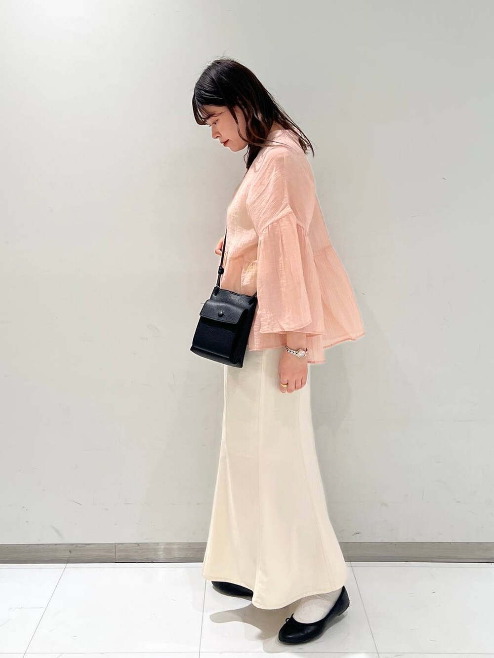 ブラック系のショルダーバッグ、ブラック系のバレエシューズ、ホワイト系のスカートを着用したレディースの春コーディネートの4枚目の写真