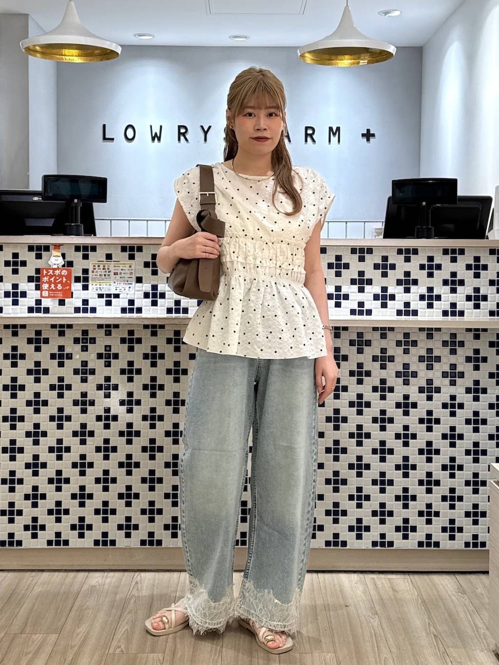 ブルー系のデニムパンツ、ホワイト系のサンダル、ブラウン系のショルダーバッグを着用したレディースの夏コーディネートの3枚目の写真