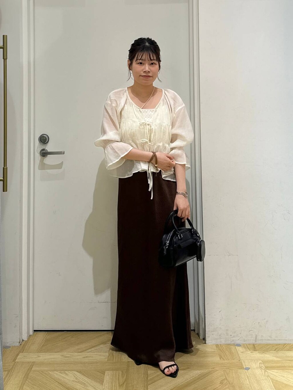 ブラック系のサンダル、ホワイト系のシャツ/ブラウス、ブラウン系のスカートを着用したレディースの夏コーディネートの2枚目の写真