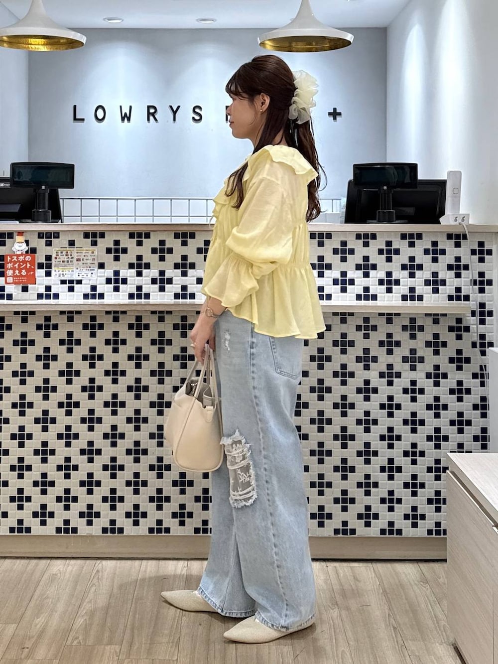 ホワイト系のショルダーバッグ、ブルー系のデニムパンツ、ホワイト系のパンプスを着用したレディースの春コーディネートの2枚目の写真