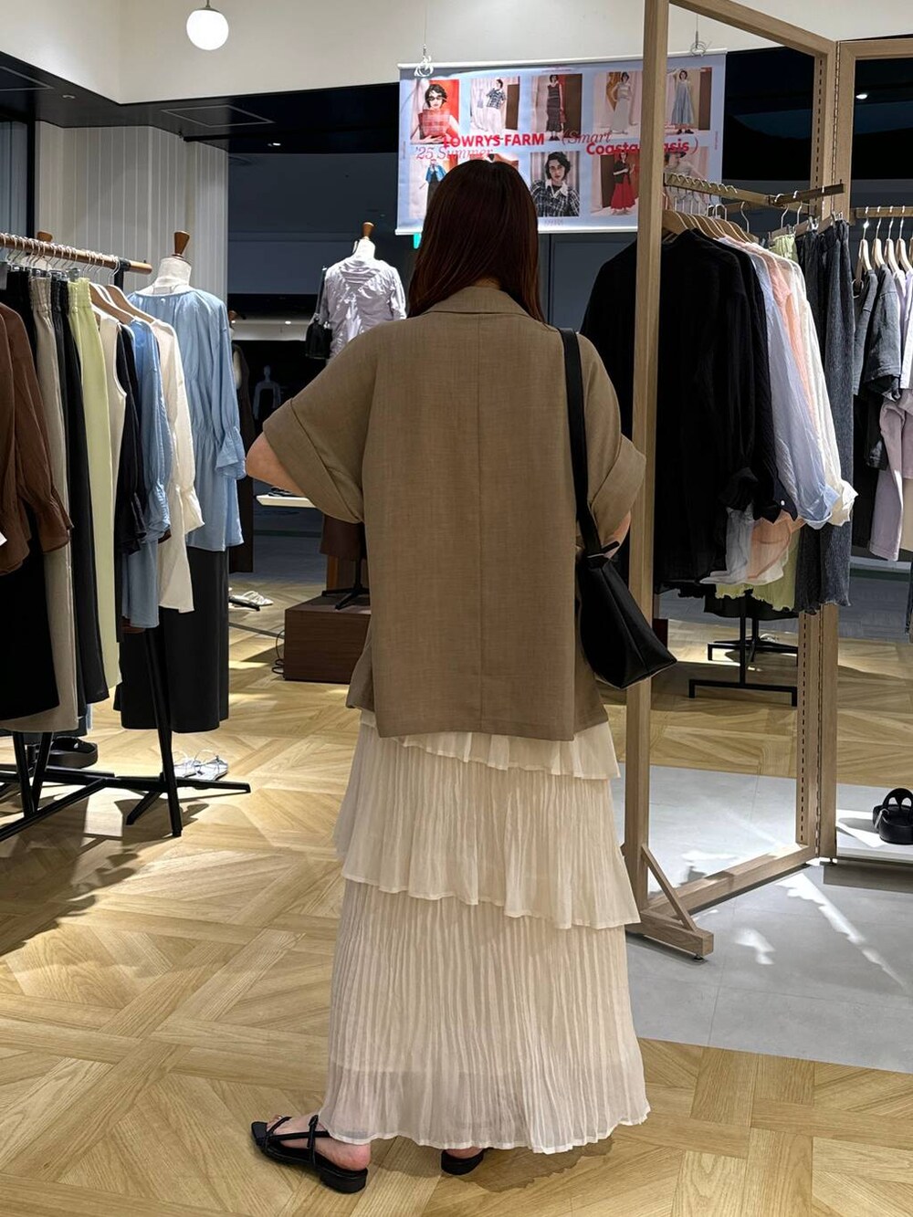 ブラック系のサンダル、ブラック系のショルダーバッグ、ベージュ系のテーラードジャケットを着用したレディースの夏コーディネートの3枚目の写真