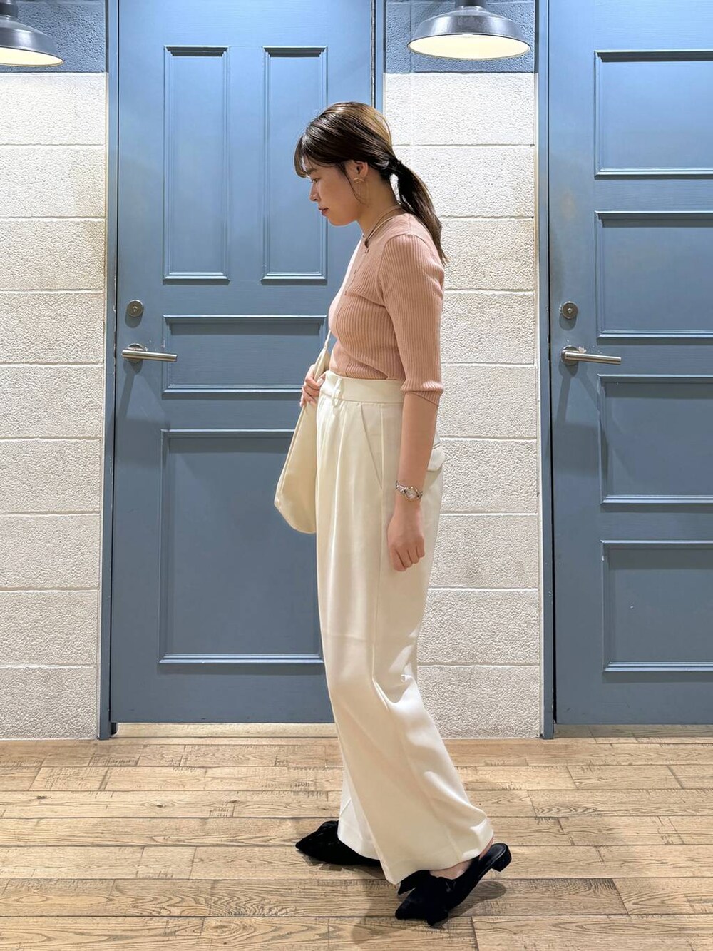 ブラック系のパンプス、ホワイト系のショルダーバッグ、ホワイト系のスラックスを着用したレディースの夏コーディネートの3枚目の写真