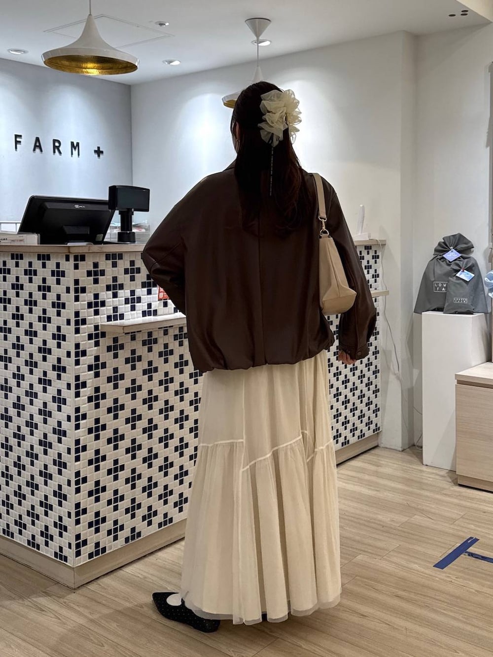 ブラック系のパンプス、ベージュ系のショルダーバッグ、ホワイト系のブルゾンを着用したレディースの春コーディネートの4枚目の写真