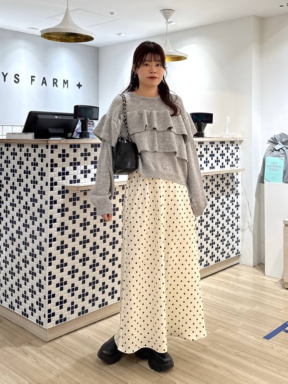 ブラック系のブーツ、ホワイト系のスカート、ブラック系のショルダーバッグを着用したレディースの冬コーディネートの3枚目の写真