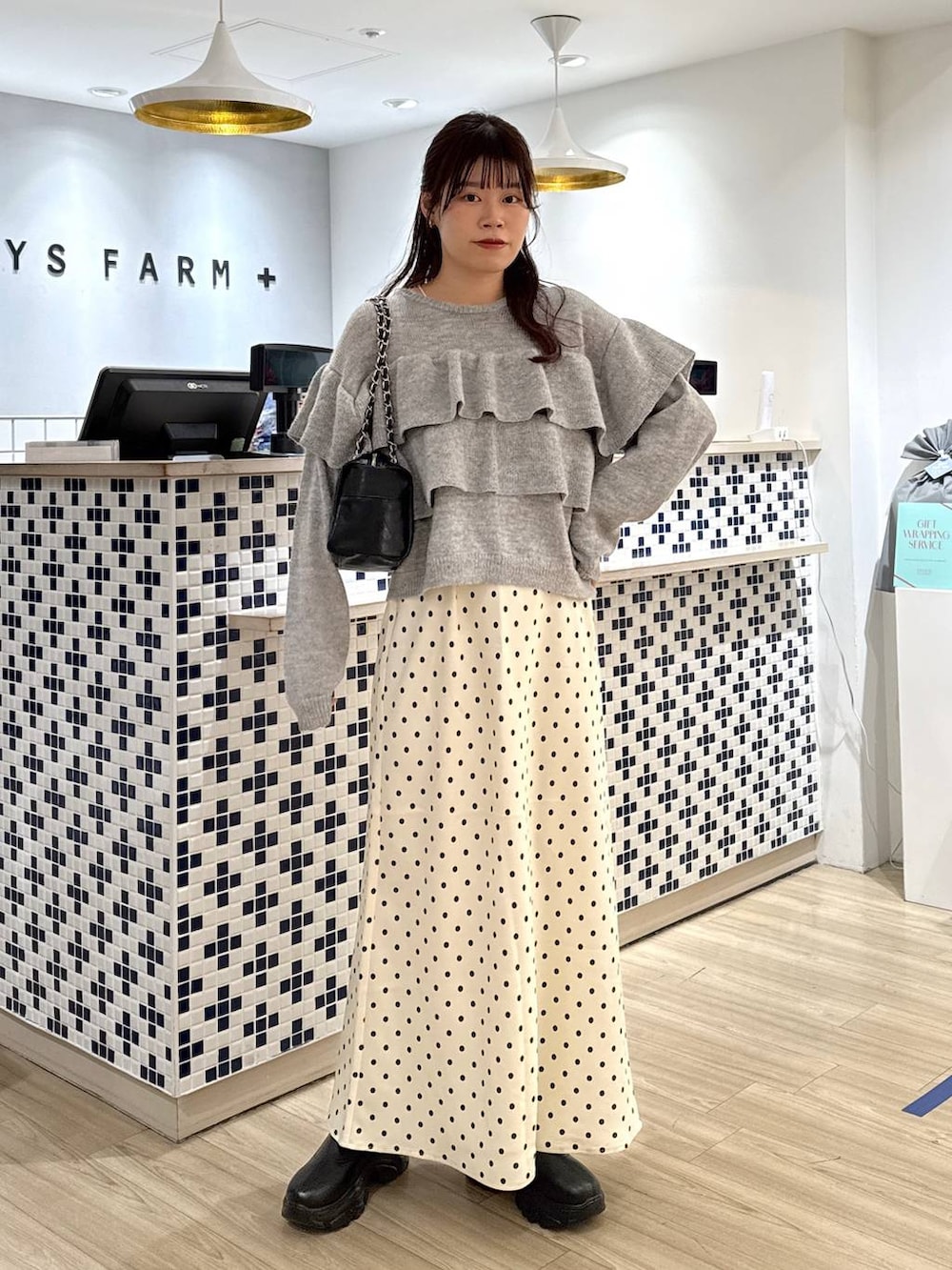 ブラック系のブーツ、ホワイト系のスカート、ブラック系のショルダーバッグを着用したレディースの冬コーディネートの2枚目の写真