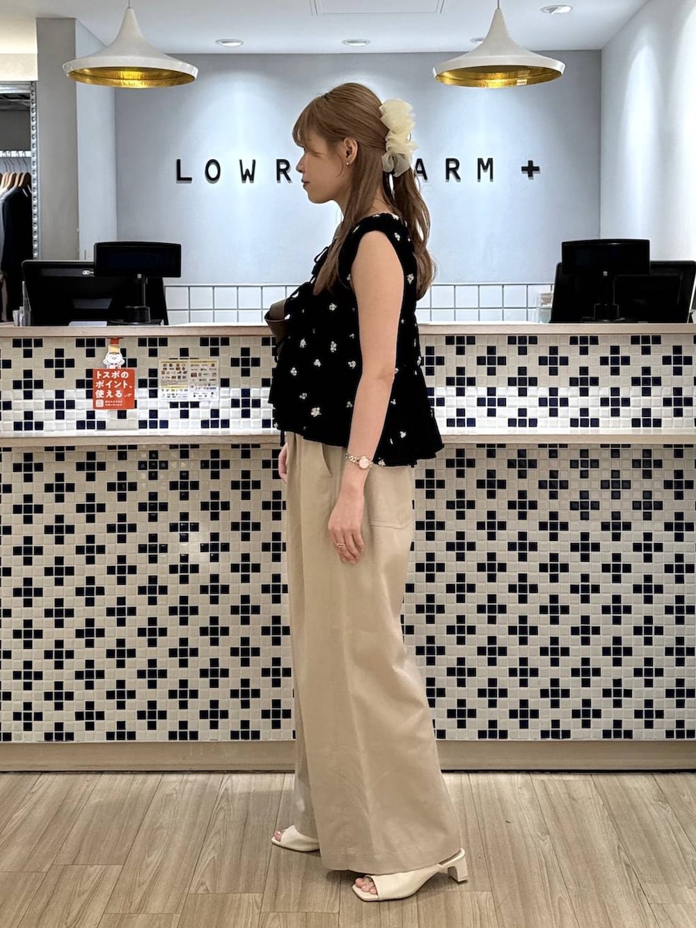 ベージュ系のデニムパンツ、ブラウン系のショルダーバッグ、ホワイト系のサンダルを着用したレディースの夏コーディネートの4枚目の写真