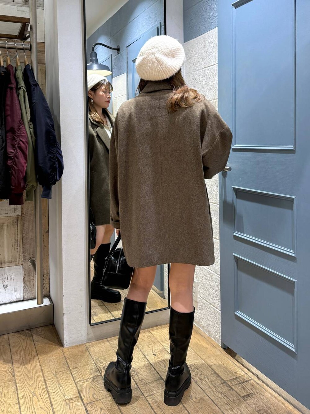 ブラウン系のチェスターコート、ホワイト系のその他パンツ、ブラック系のブーツを着用したレディースの秋コーディネートの5枚目の写真