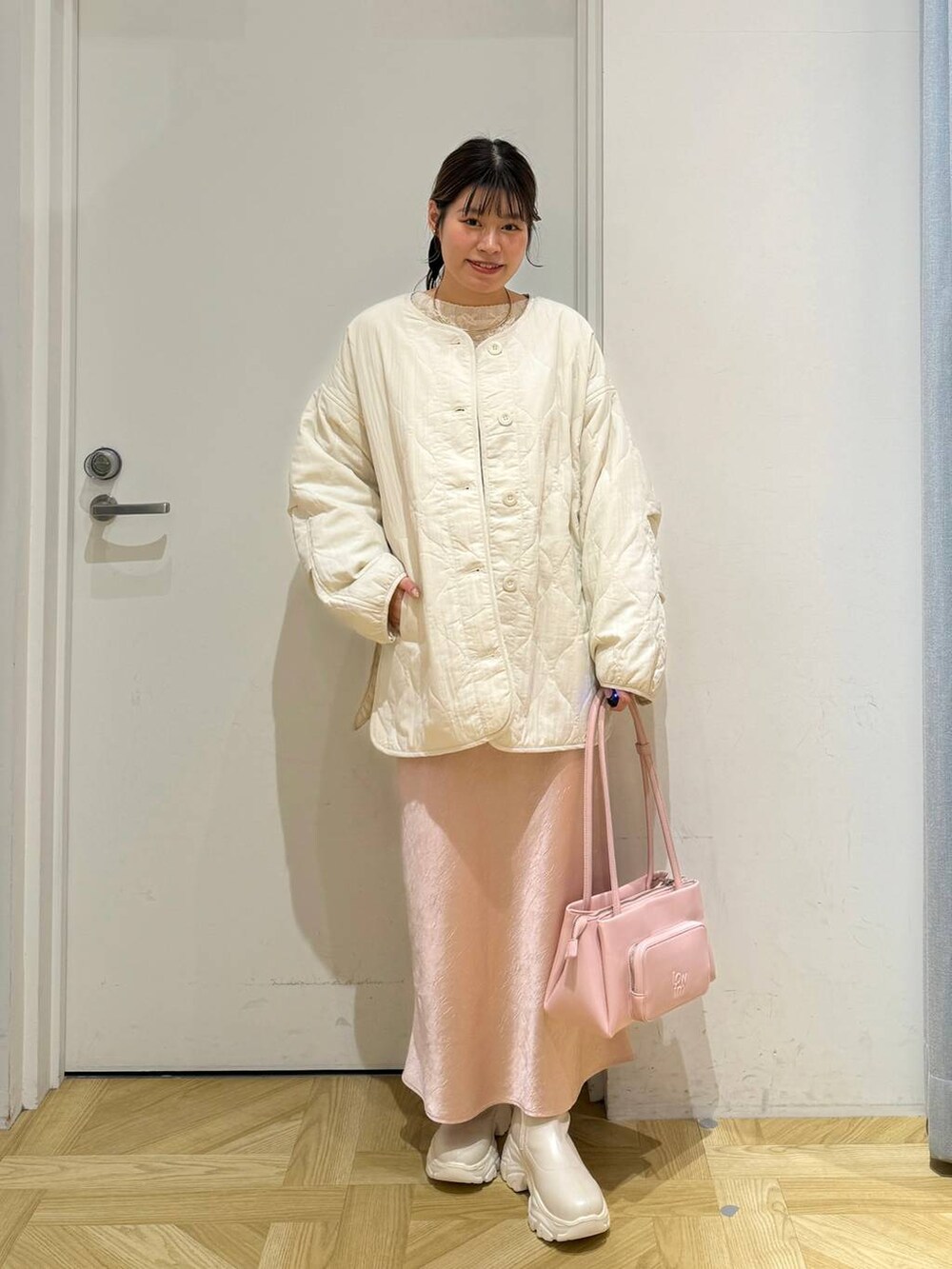 ホワイト系のブルゾン、ピンク系のショルダーバッグ、ホワイト系のブーツを着用したレディースの冬コーディネートの2枚目の写真