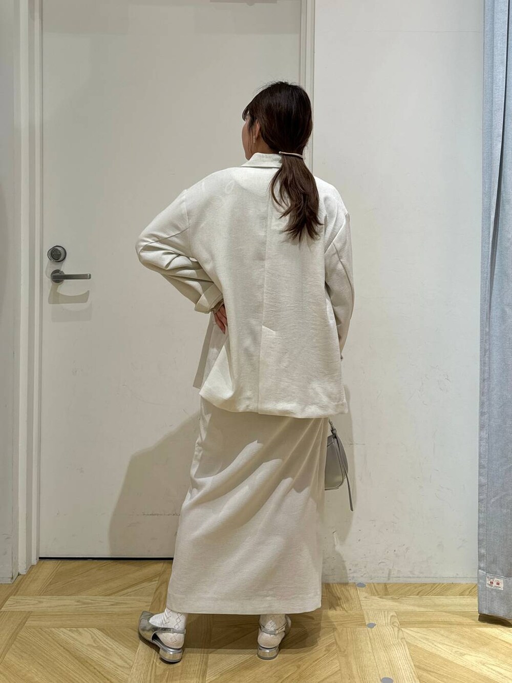 ホワイト系のスカート、ホワイト系のテーラードジャケット、シルバー系のトートバッグを着用したレディースの春コーディネートの4枚目の写真