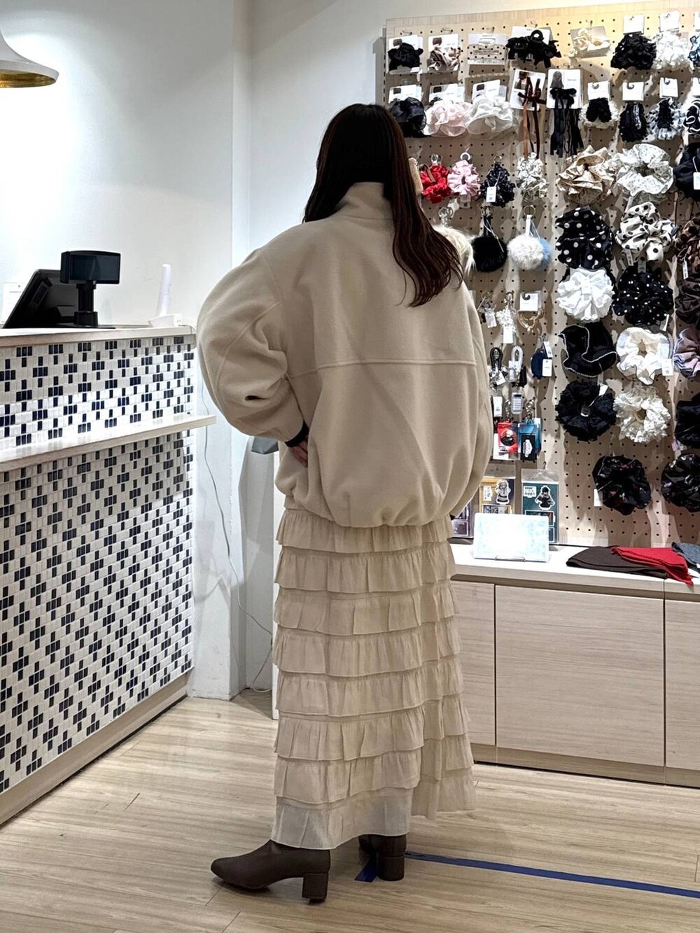 ホワイト系のブルゾン、ホワイト系のスカート、ブラウン系のポロシャツを着用したレディースの秋コーディネートの5枚目の写真