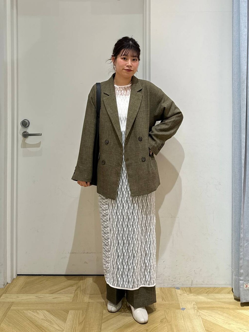 ブラック系のショルダーバッグ、ホワイト系のブーツ、ブラウン系のスラックスを着用したレディースの春コーディネートの2枚目の写真