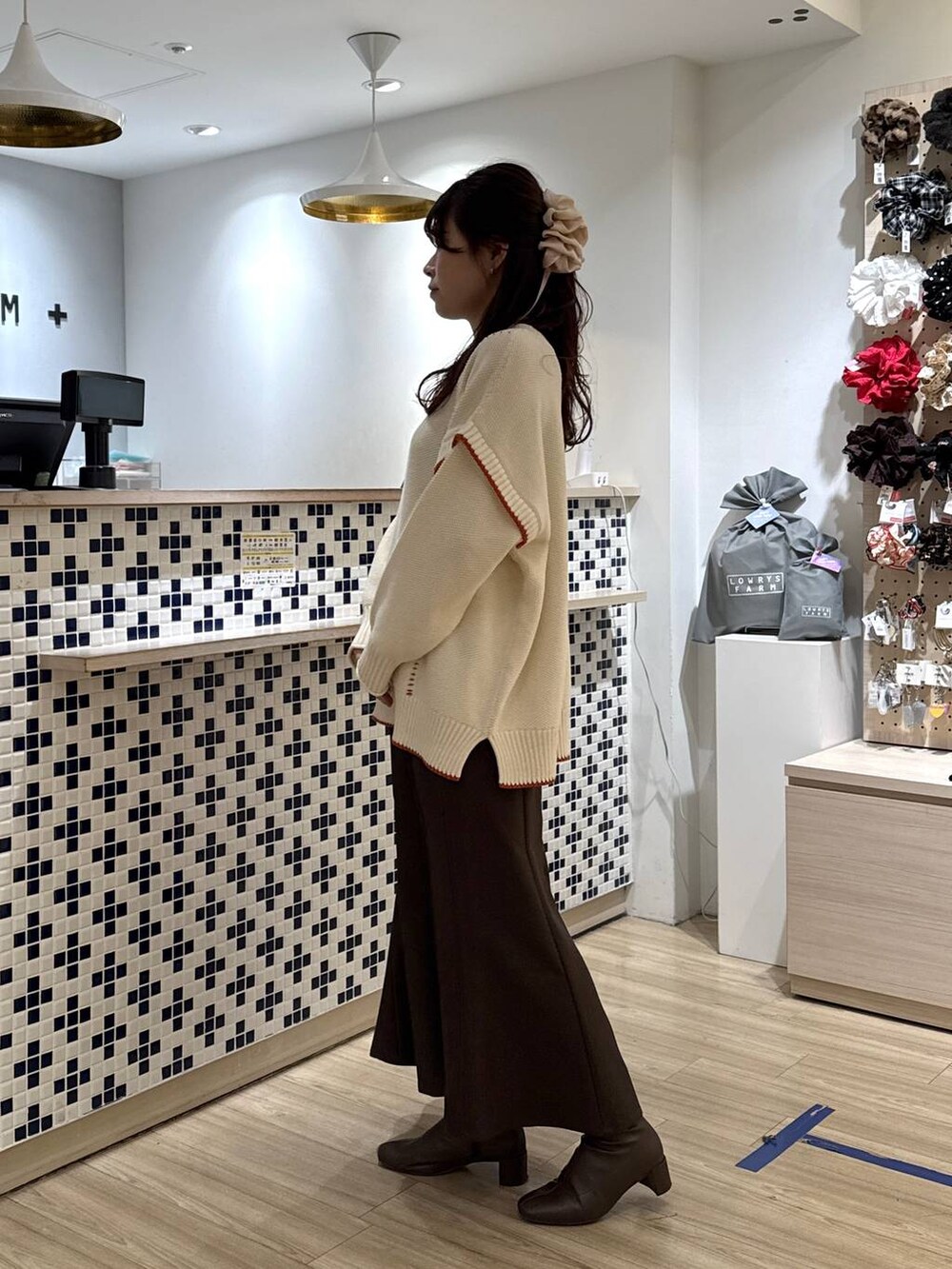 ホワイト系のニット/セーター、ブラウン系のスカート、ブラウン系のブーツを着用したレディースの冬コーディネートの3枚目の写真