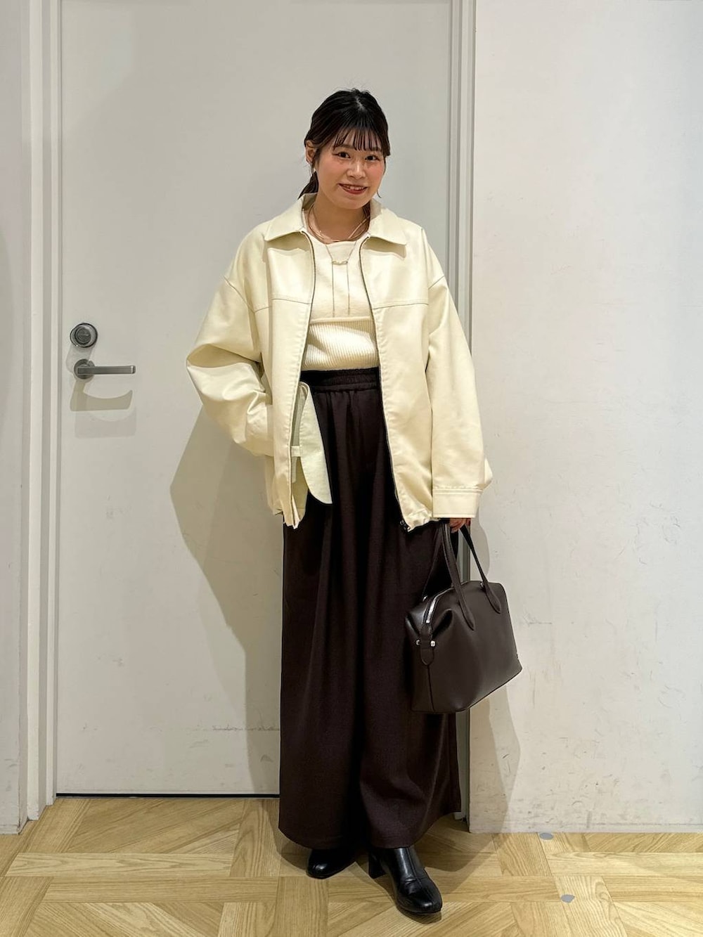 ブラック系のブーツ、ブラウン系のショルダーバッグ、ホワイト系のブルゾンを着用したレディースの冬コーディネートの2枚目の写真