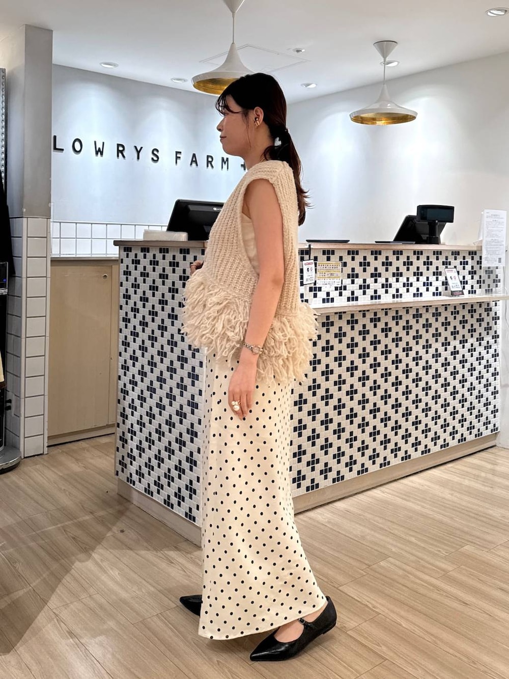 ホワイト系のスカート、ブラウン系のショルダーバッグ、ブラック系のパンプスを着用したレディースの秋コーディネートの3枚目の写真