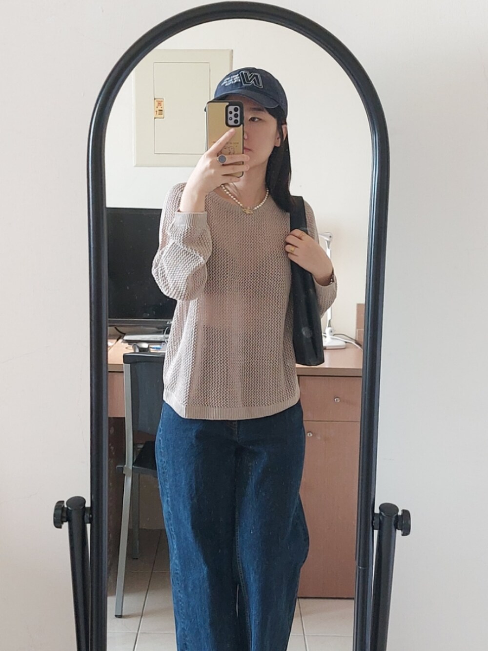 ブルー系のデニムパンツ、ベージュ系のニット/セーター、ブラック系のショルダーバッグを着用したレディースの秋コーディネートの2枚目の写真