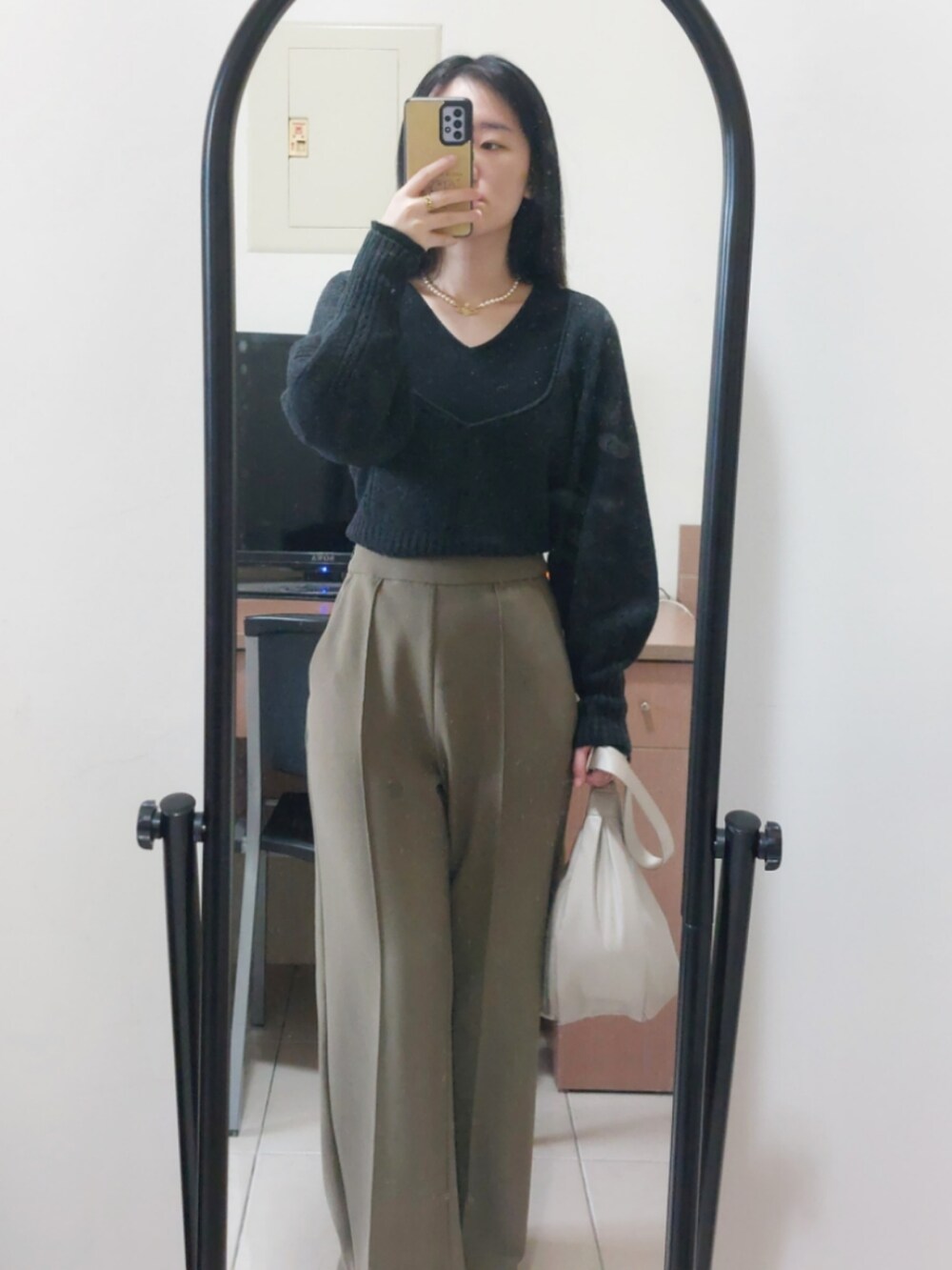 グリーン系のスラックス、ベージュ系のショルダーバッグ、ベージュ系のニット/セーターを着用したレディースの秋コーディネートの2枚目の写真