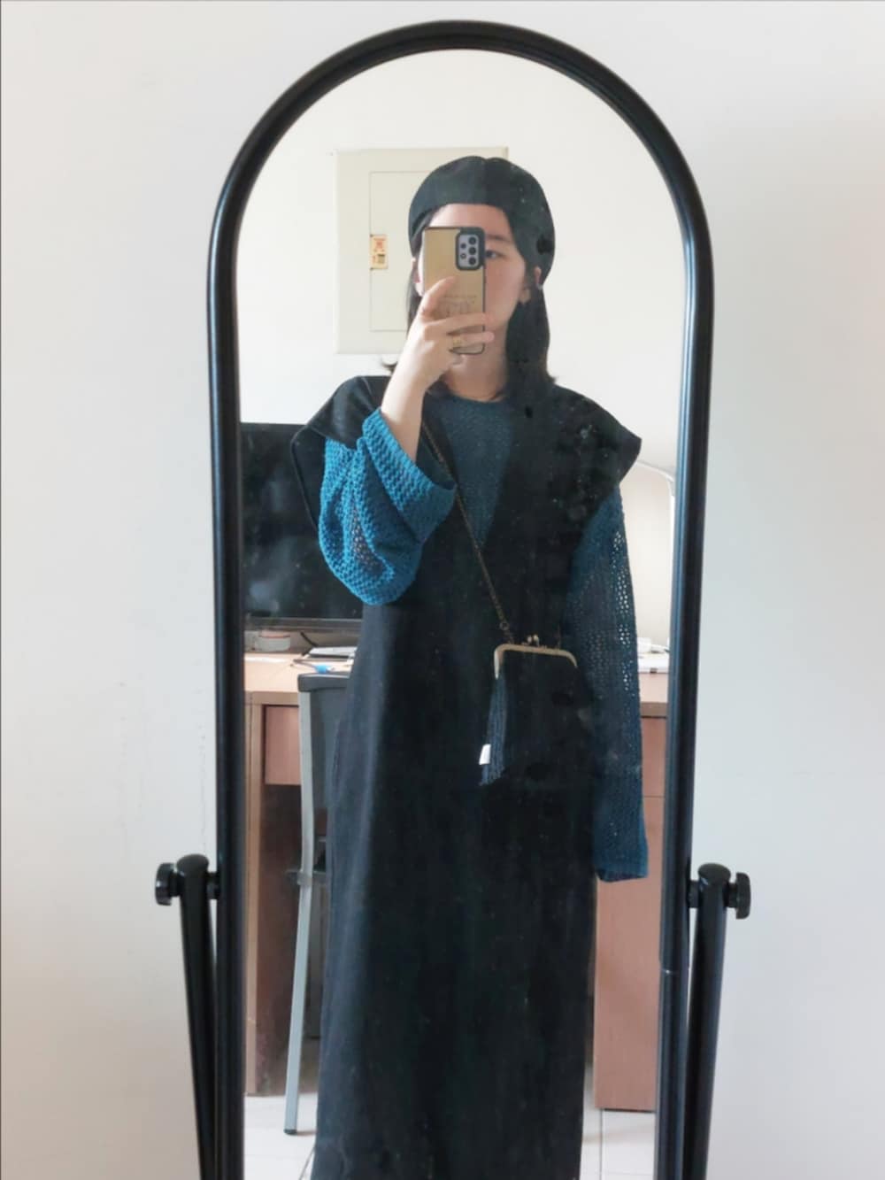 ブラック系のジャンパースカート、ブラック系のショルダーバッグ、ブルー系のニット/セーターを着用したレディースの秋コーディネートの2枚目の写真