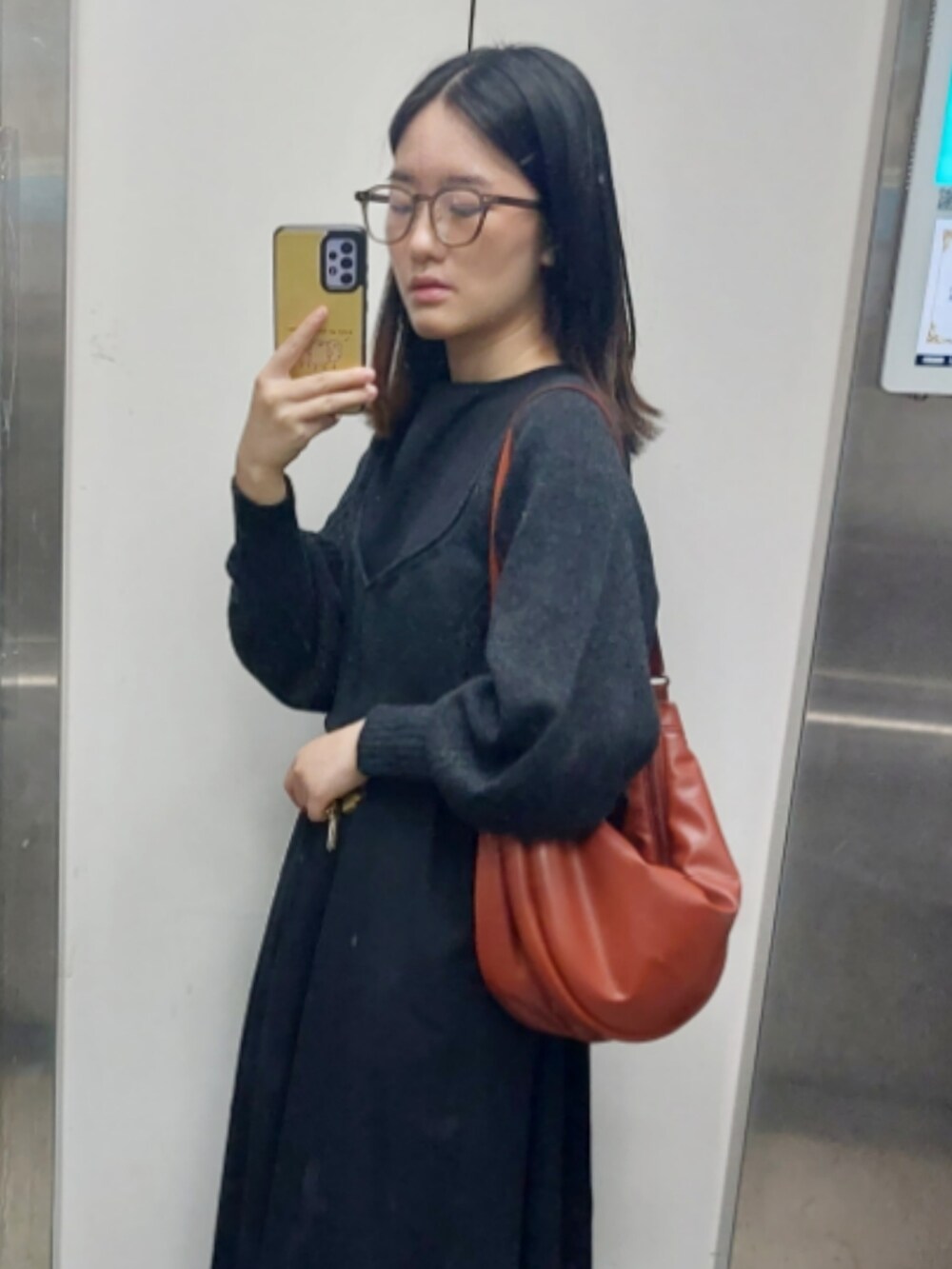 レッド系のショルダーバッグ、ベージュ系のニット/セーター、ブラック系のワンピースを着用したレディースの秋コーディネートの3枚目の写真