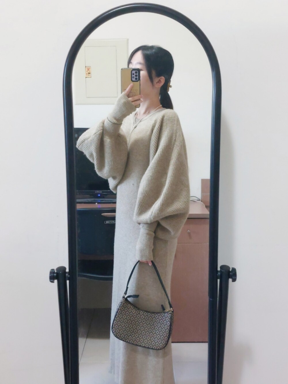 グレー系のワンピース、ブラウン系のハンドバッグを着用したレディースの秋コーディネートの2枚目の写真