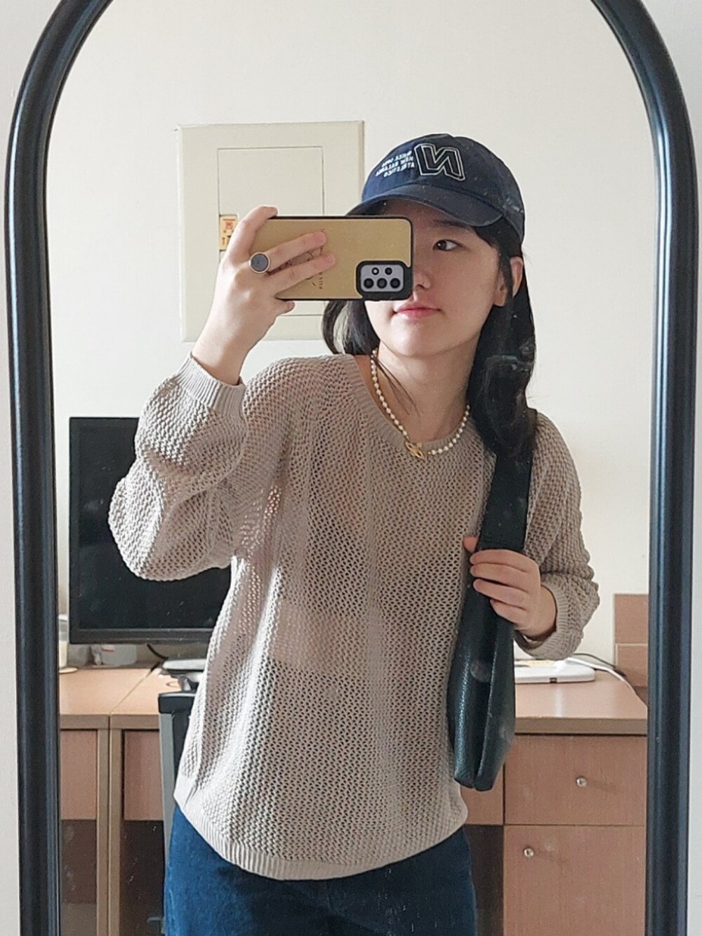 ブルー系のデニムパンツ、ベージュ系のニット/セーター、ブラック系のショルダーバッグを着用したレディースの秋コーディネートの3枚目の写真