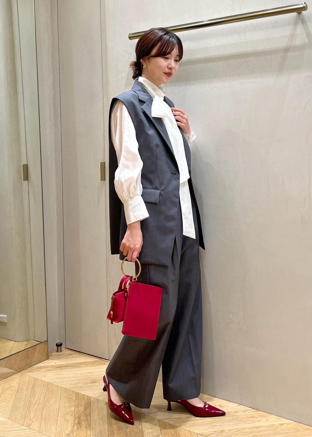 レッド系のパンプス、グレー系のベスト、グレー系のその他パンツを着用したレディースの秋コーディネートの2枚目の写真
