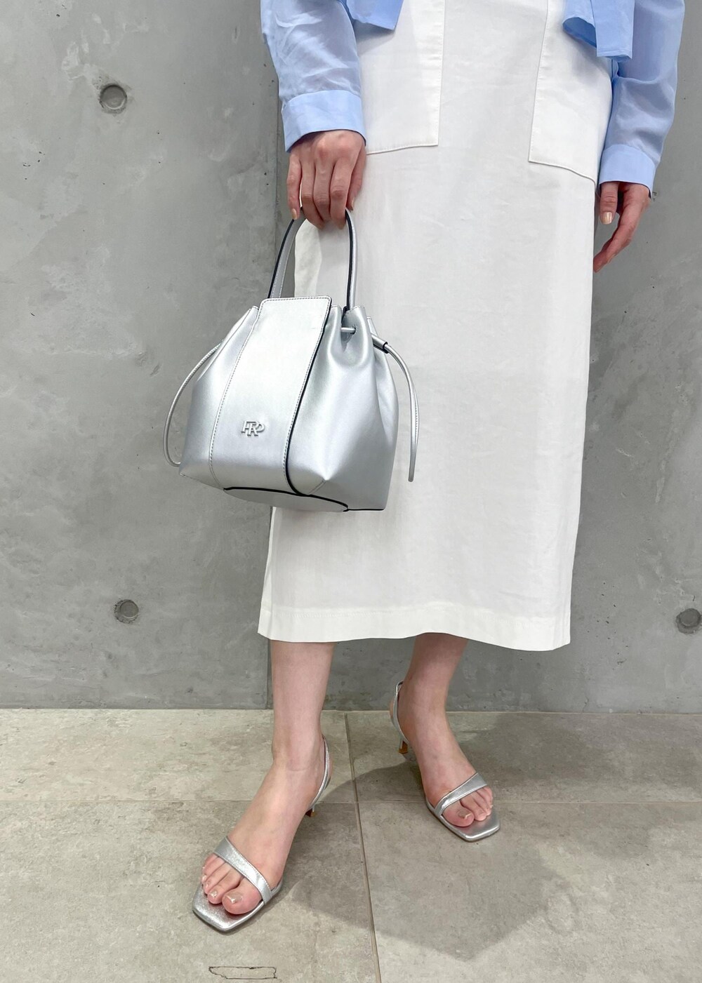 シルバー系のサンダル、ホワイト系のスカート、シルバー系のハンドバッグを着用したレディースの夏コーディネートの8枚目の写真