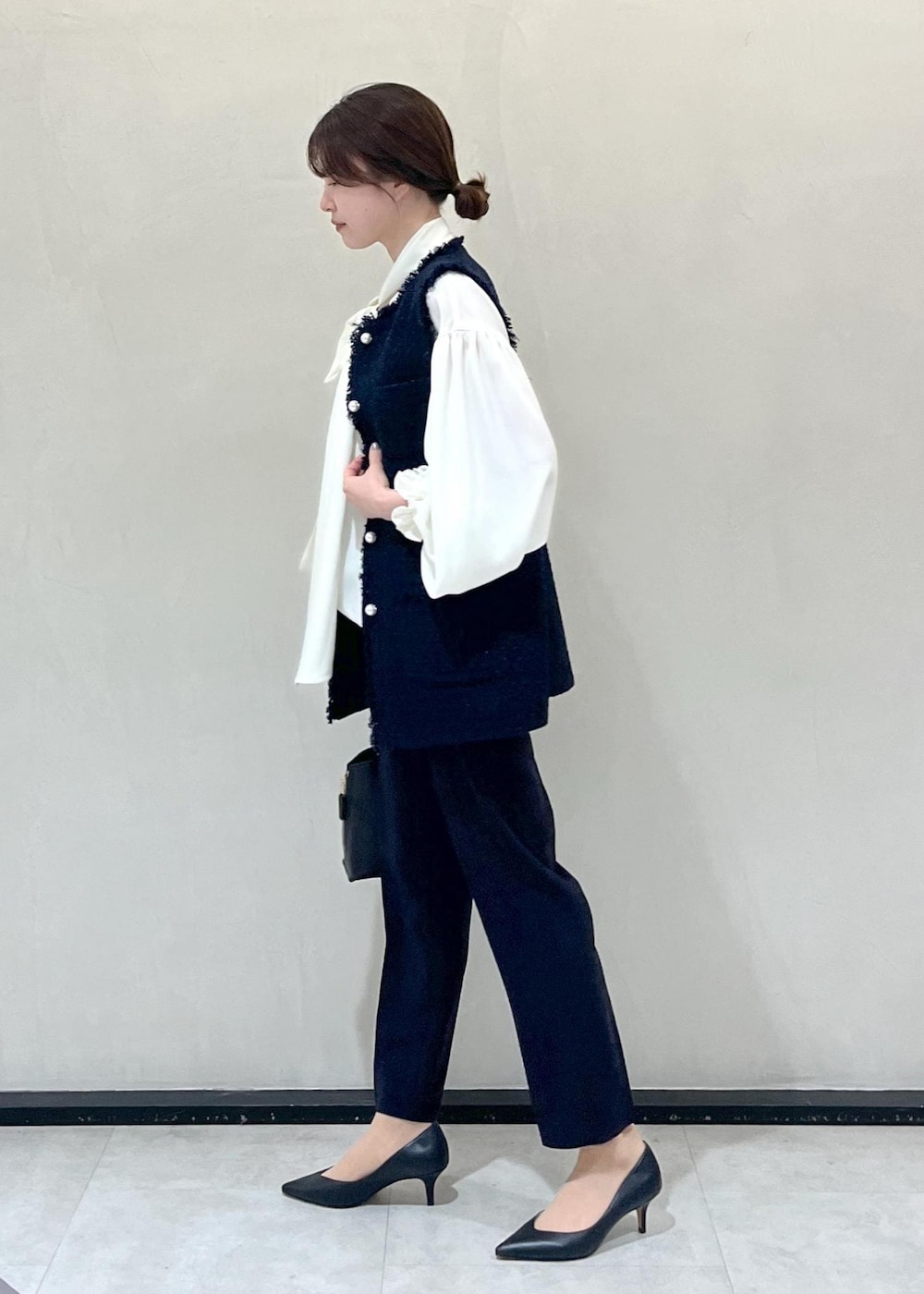 ブラック系のパンプス、ブラック系のハンドバッグ、ホワイト系のシャツ/ブラウスを着用したレディースの冬コーディネートの2枚目の写真