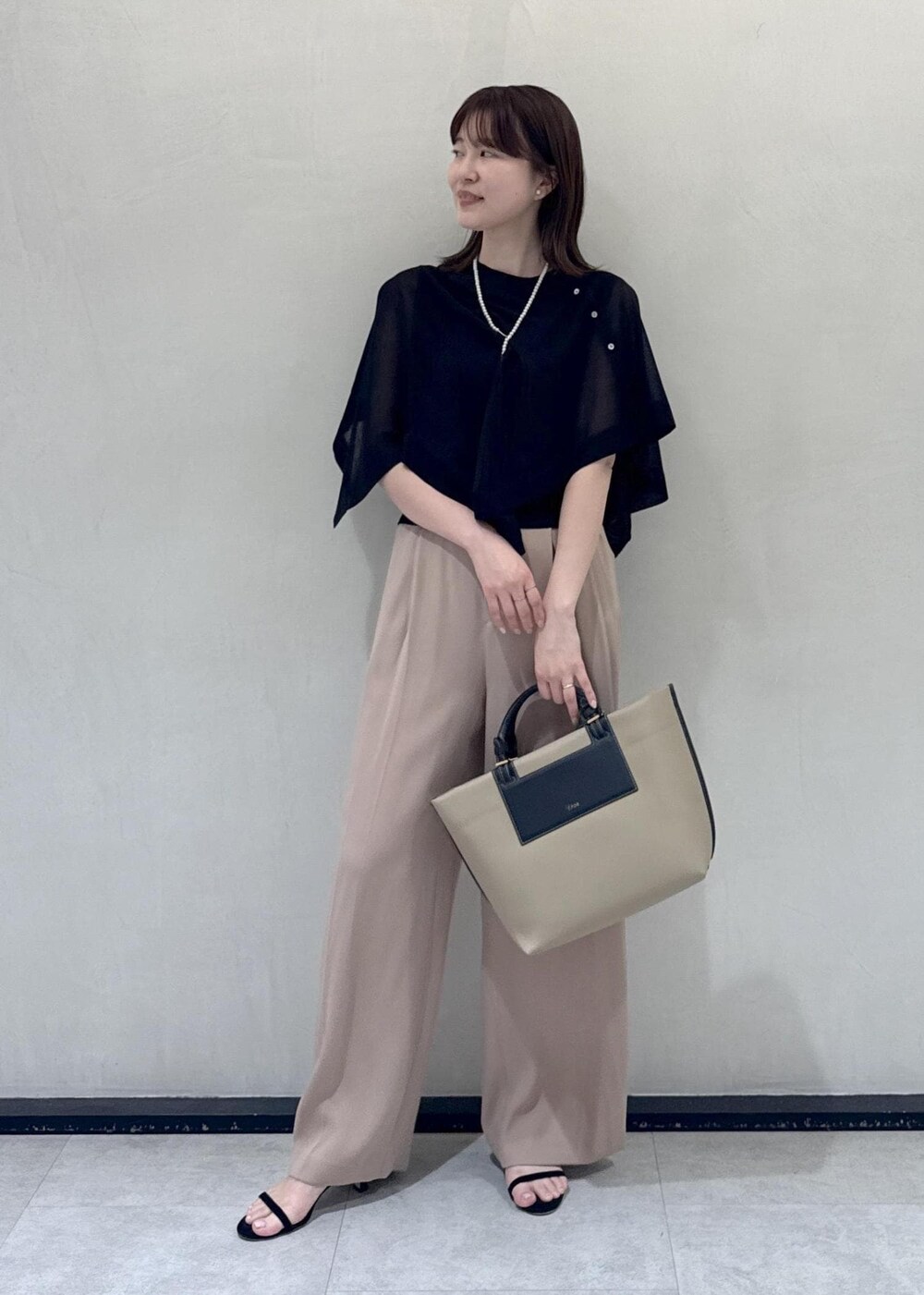 ベージュ系のトートバッグ、ベージュ系のその他パンツ、ブラック系のTシャツ/カットソーを着用したレディースの春コーディネートの2枚目の写真