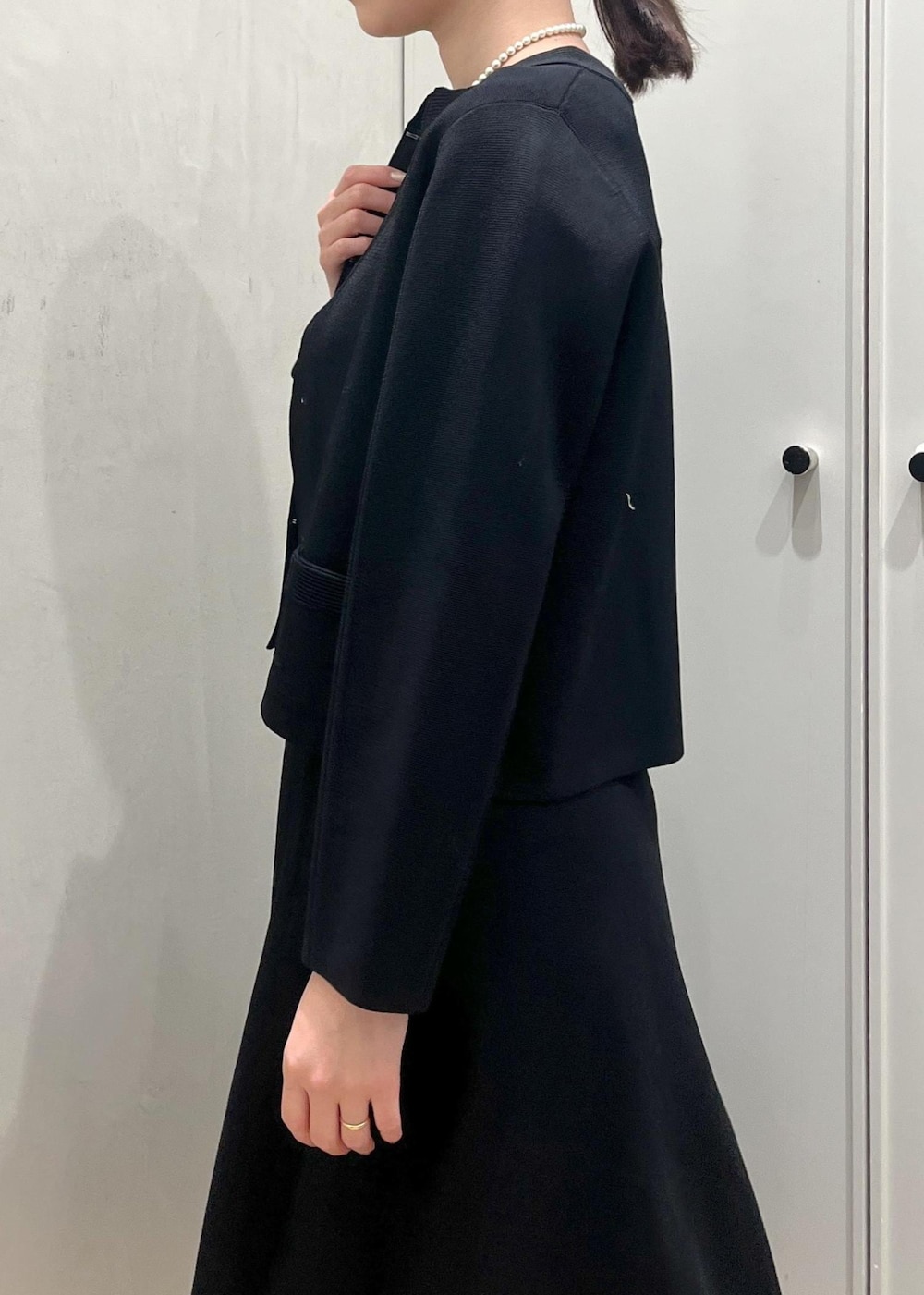 ブラック系のハンドバッグ、ブラック系のパンプス、ブルー系のワンピースを着用したレディースの冬コーディネートの5枚目の写真