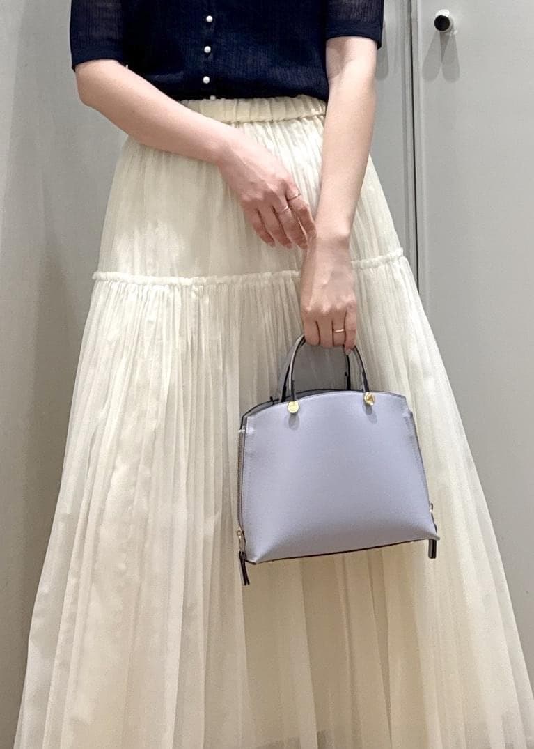 パープル系のハンドバッグ、ベージュ系のスカート、ブルー系のカーディガン/ボレロを着用したレディースの春コーディネートの8枚目の写真
