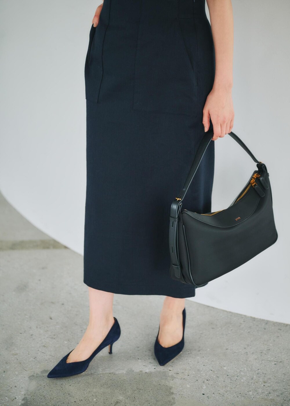 ブルー系のスカート、ブラック系のハンドバッグ、ベージュ系のシャツ/ブラウスを着用したレディースの春コーディネートの4枚目の写真