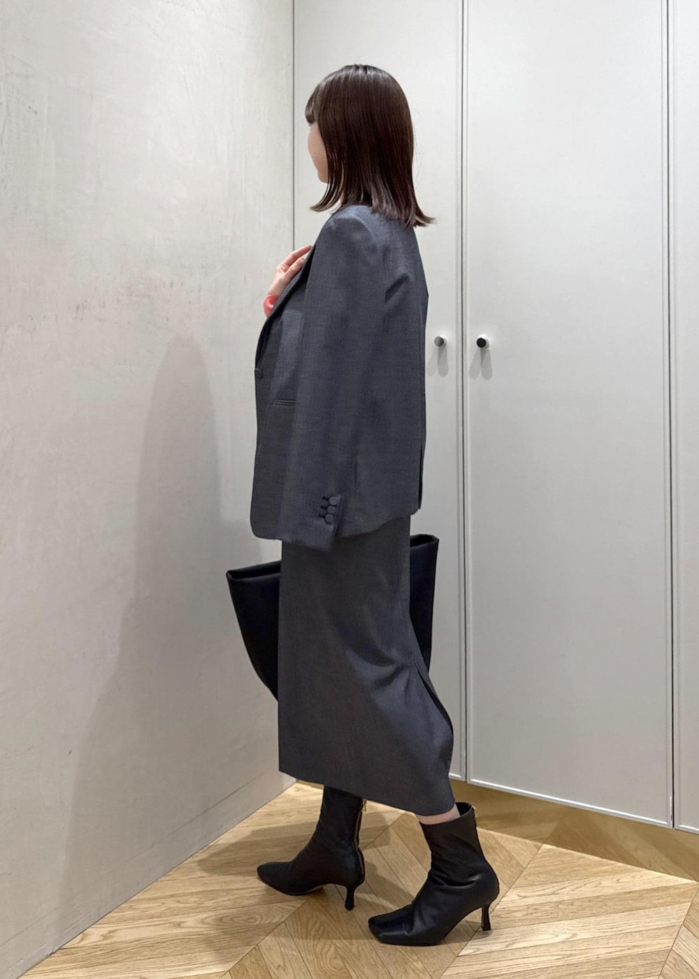 ブラック系のトートバッグ、ブルー系のテーラードジャケット、ブルー系のスカートを着用したレディースの冬コーディネートの2枚目の写真