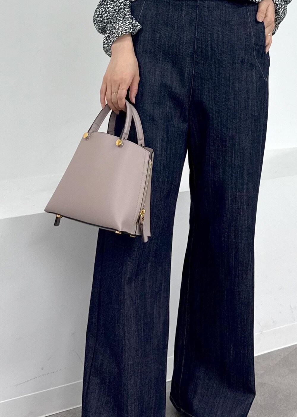 グレー系のハンドバッグ、ブラウン系のブーツ、ブルー系のデニムパンツを着用したレディースの秋コーディネートの8枚目の写真