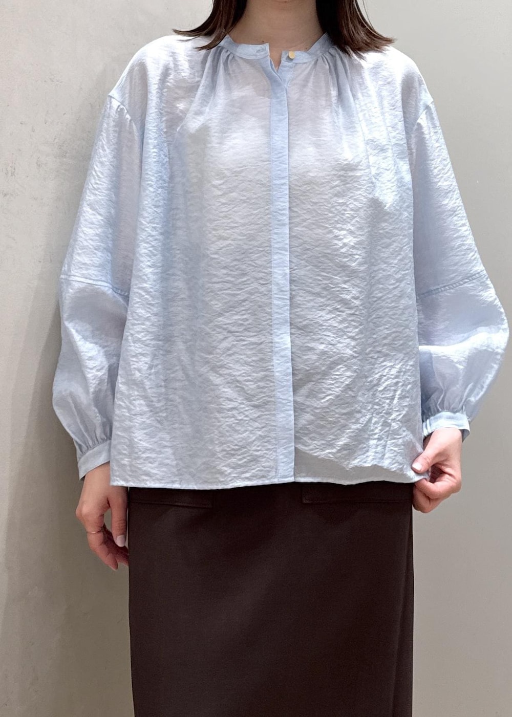 ブラウン系のスカート、ベージュ系のハンドバッグ、ブルー系のシャツ/ブラウスを着用したレディースの春コーディネートの5枚目の写真