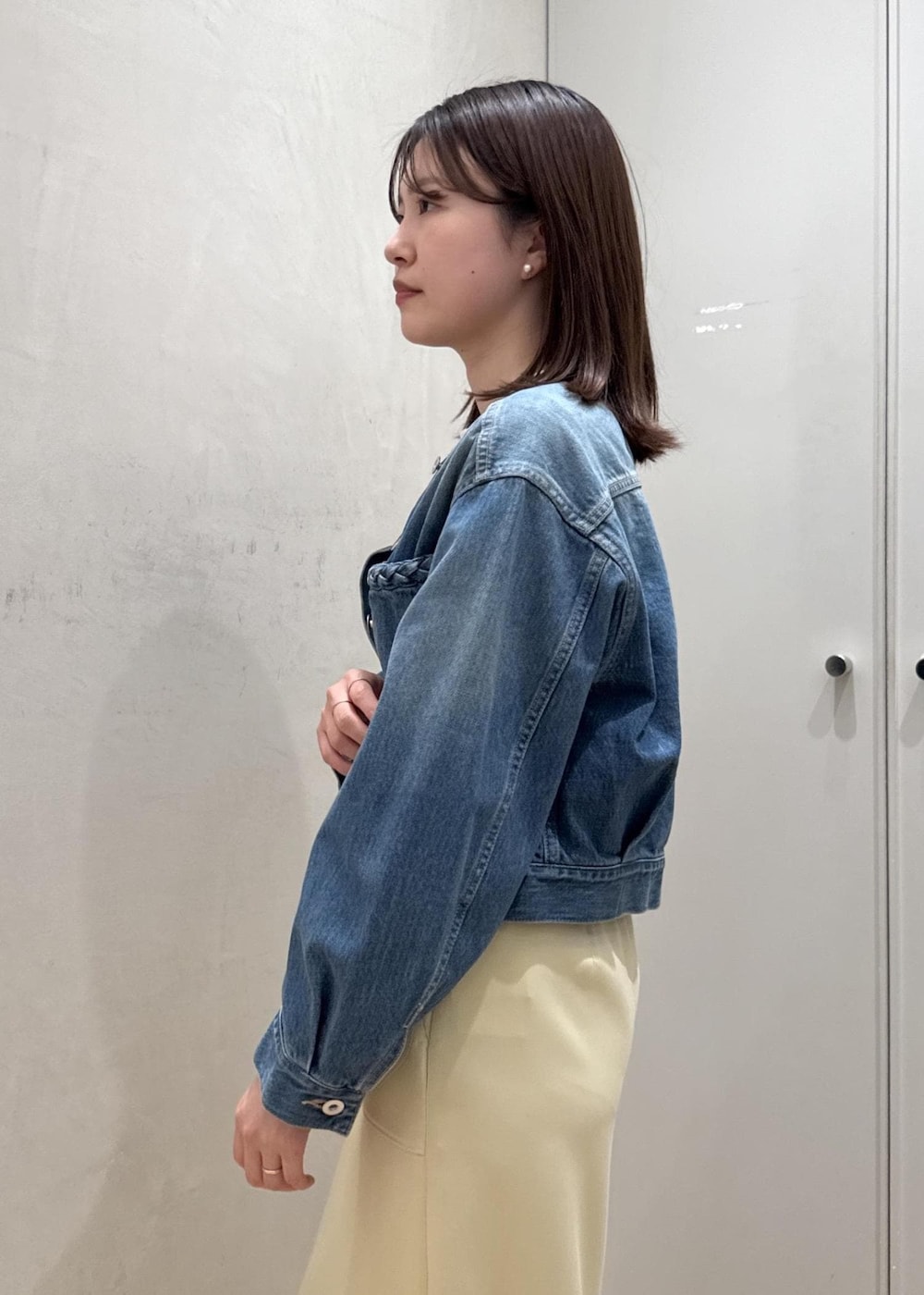 ベージュ系のショルダーバッグ、イエロー系のスカート、ブルー系のデニムジャケットを着用したレディースの春コーディネートの5枚目の写真