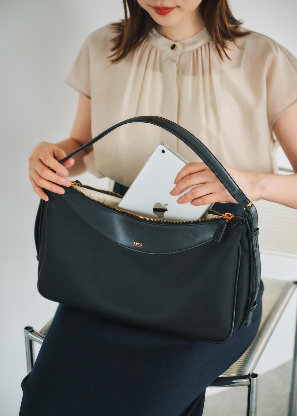 ブルー系のスカート、ブラック系のハンドバッグ、ベージュ系のシャツ/ブラウスを着用したレディースの春コーディネートの6枚目の写真