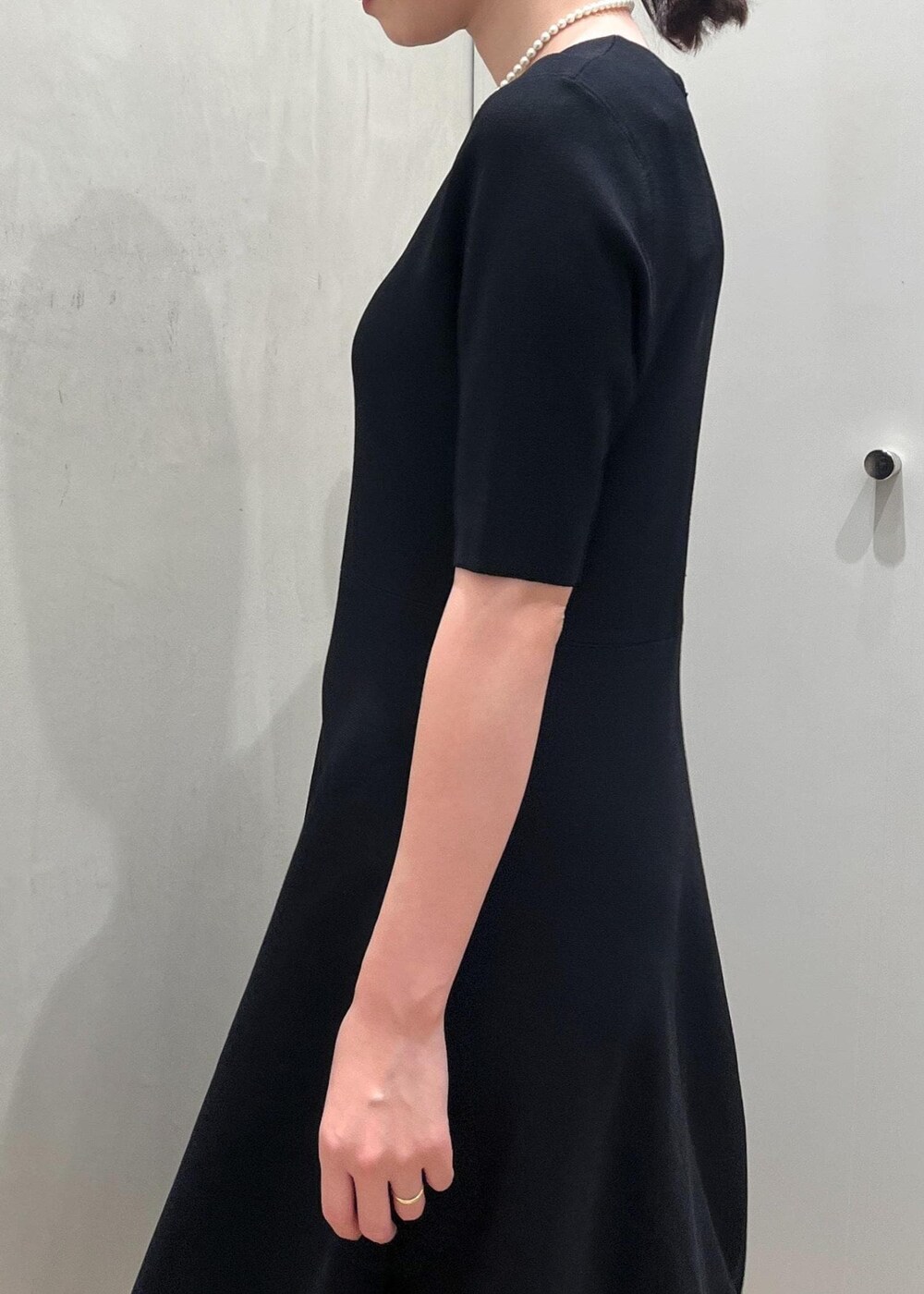ブラック系のハンドバッグ、ブラック系のパンプス、ブルー系のワンピースを着用したレディースの冬コーディネートの7枚目の写真
