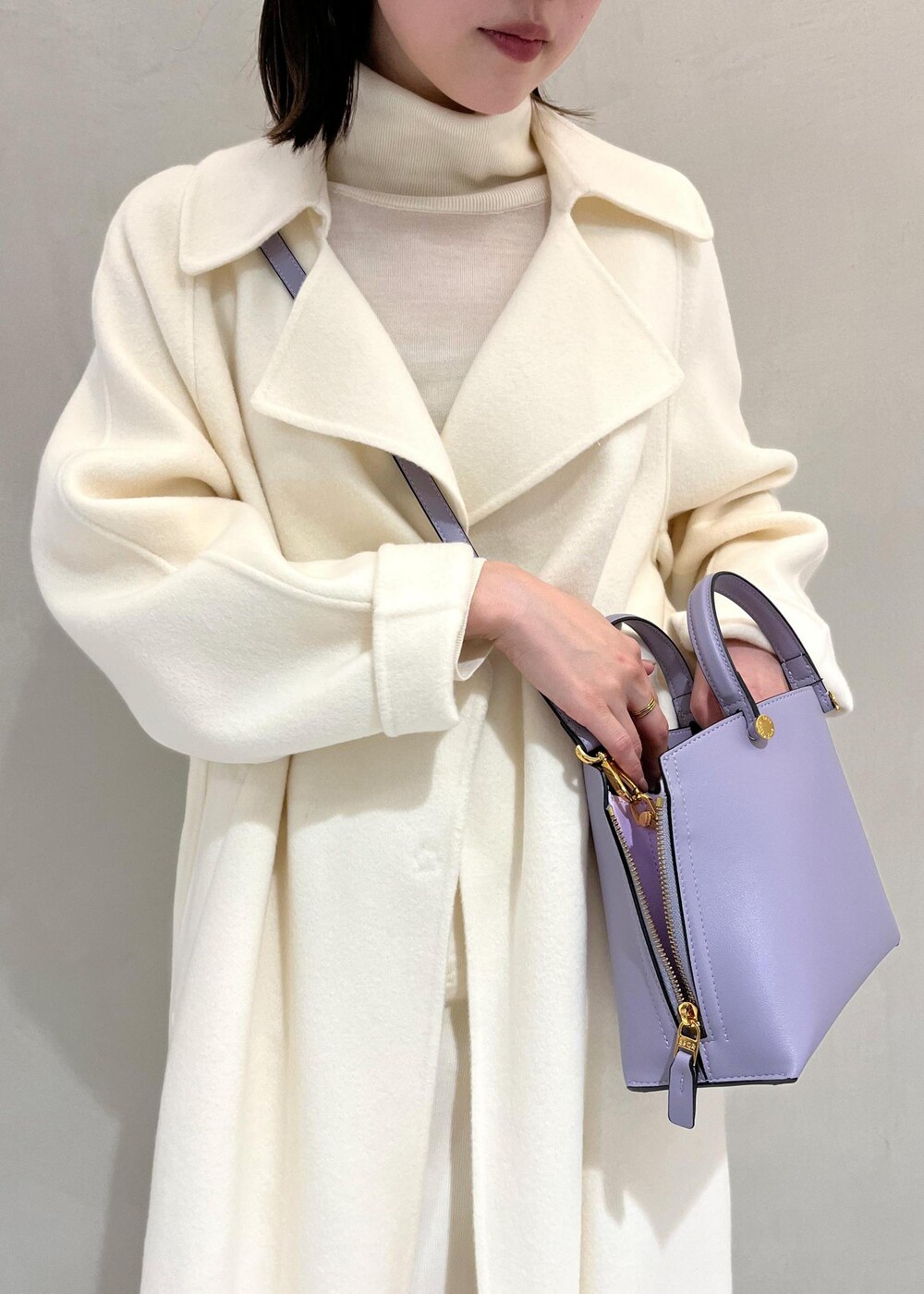 ブラック系のブーツ、ホワイト系のチェスターコート、ホワイト系のスカートを着用したレディースの秋コーディネートの5枚目の写真