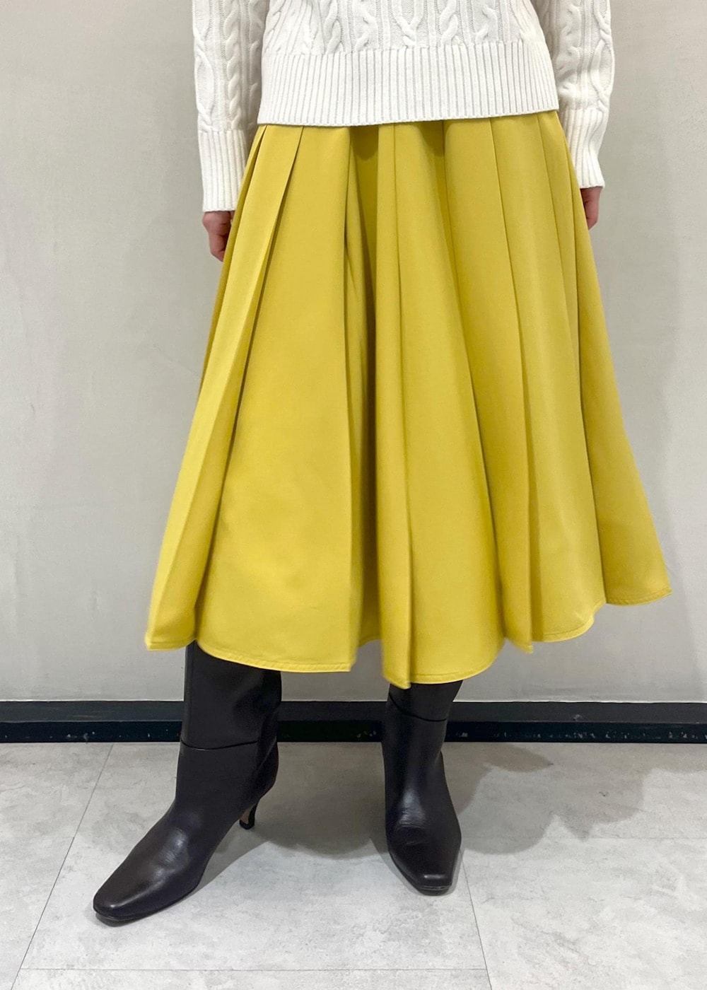 ブラウン系のブーツ、イエロー系のスカート、ブラック系のバックパック/リュックを着用したレディースの冬コーディネートの5枚目の写真