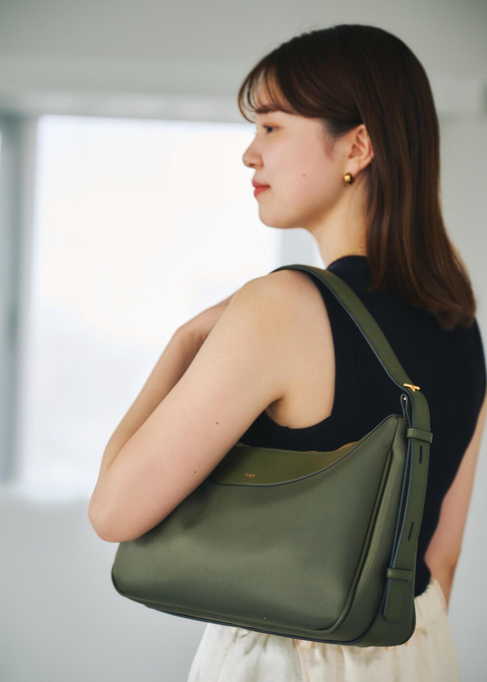 ブルー系のニット/セーター、グリーン系のハンドバッグ、ホワイト系のスカートを着用したレディースの春コーディネートの5枚目の写真